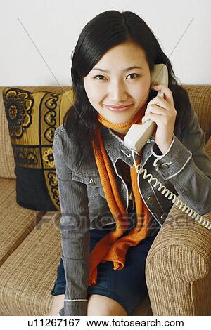 Stock Photo - Portrait of a young woman using a telephone. Fotosearch