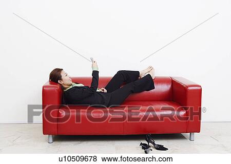 Side profile of a businesswoman lying on a couch and operating a mobile phone View Large Photo Image Stock Photo - Side profile of a businesswoman lying on a couch and operating a mobile phone. Fotosearch