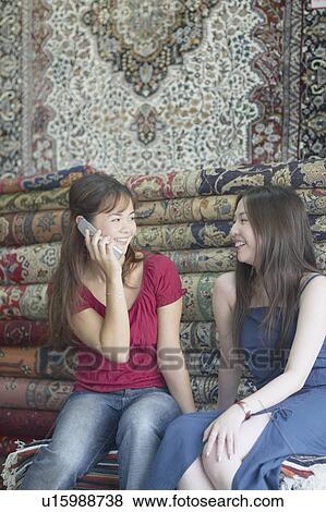 Stock Photo - Two young women sitting in a carpet store. Fotosearch