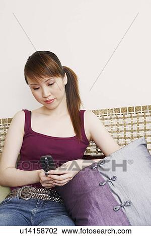 Stock Image - Young woman holding a mobile phone. Fotosearch