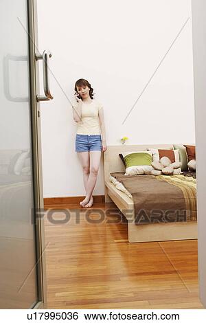 Young woman leaning against a wall and talking on the mobile phone View Large Photo Image Stock Photograph - Young woman leaning against a wall and talking on the mobile phone. Fotosearch
