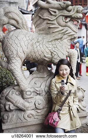 Young woman smiling while holding a mobile phone View Large Photo Image Stock Image - Young woman smiling while holding a mobile phone. Fotosearch