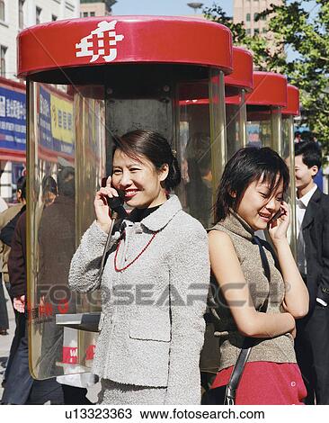 Young woman talking on a pay phone with another young woman talking on a mobile phone View Large Photo Image Stock Image - Young woman talking on a pay phone with another young woman talking on a mobile phone. Fotosearch