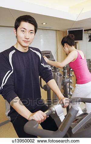 Stock Image - Close-up of a young man and a young woman exercising in a gym. Fotosearch