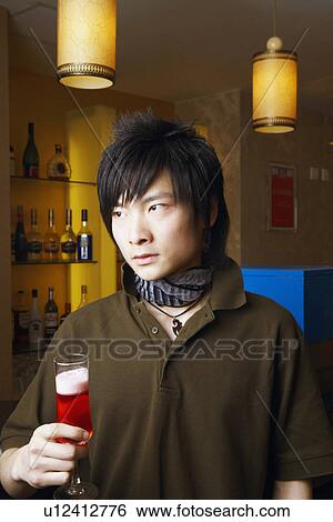 Close-up of a young man holding a glass View Large Photo Image Stock Photograph - Close-up of a young man holding a glass. Fotosearch