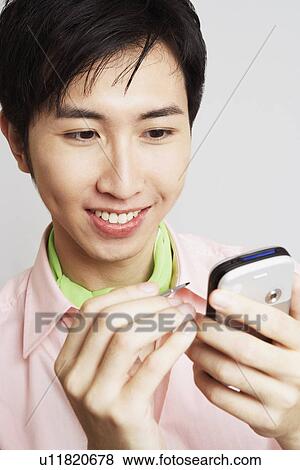 Close-up of a young man holding a digitized pen and a mobile phone View Large Photo Image Stock Photo - Close-up of a young man holding a digitized pen and a mobile phone. Fotosearch