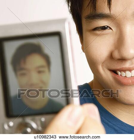 Stock Image - Close-up of a young man taking a picture of himself . Fotosearch
