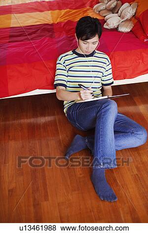 High angle view of a young man listening to music and reading a diary View Large Photo Image Stock Photo - High angle view of a young man listening to music and reading a diary. Fotosearch