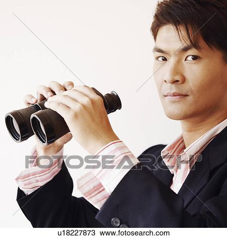 Stock Image - Portrait of a businessman holding a pair of binoculars. Fotosearch