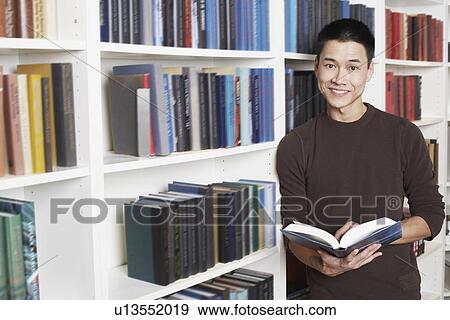 Stock Photo - Portrait of a businessman holding a book smiling. Fotosearch