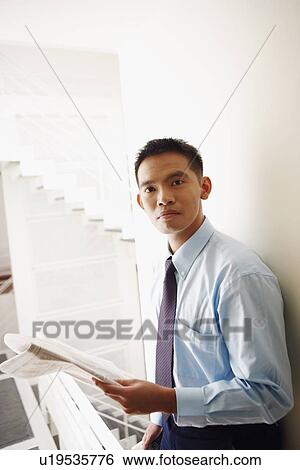 Stock Photograph - Portrait of a businessman holding a newspaper. Fotosearch
