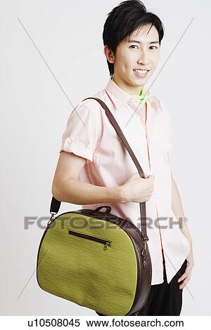 Portrait of a young man carrying a bag View Large Photo Image Stock Photography - Portrait of a young man carrying a bag. Fotosearch