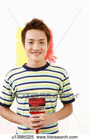 Portrait of a young man holding a paintbrush and smiling View Large Photo Image Stock Photography - Portrait of a young man holding a paintbrush and smiling. Fotosearch