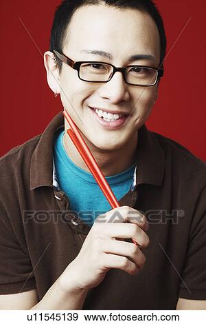 Stock Photo - Portrait of a young man holding chopsticks. Fotosearch