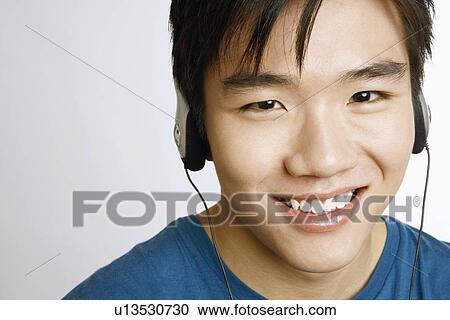 Stock Image - Portrait of a young man listening to music and smiling. Fotosearch