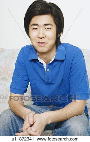Portrait of a young man sitting on a couch View Large Photo Image Stock Image - Portrait of a young man sitting on a couch. Fotosearch