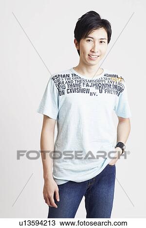 Stock Image - Portrait of a young man standing with his hands in his pockets. Fotosearch