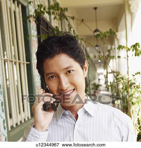 Stock Photo - Portrait of a young man talking on a mobile phone. Fotosearch