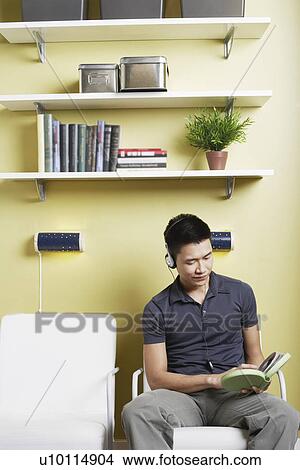 Picture - Young man listening to music on headphones. Fotosearch