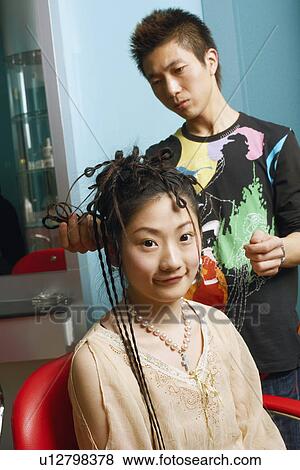 Stock Photo - Close-up of a hairdresser adjusting a young woman's hair. Fotosearch