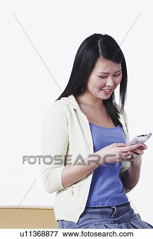 Close-up of a young woman operating a mobile phone View Large Photo Image Stock Photo - Close-up of a young woman operating a mobile phone. Fotosearch