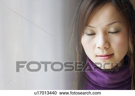 Stock Image - Close-up of a young woman with her eyes closed. Fotosearch