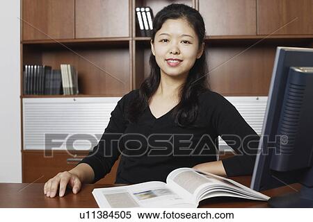 Stock Photography - Portrait of a businesswoman sitting with a magazine on the table. Fotosearch