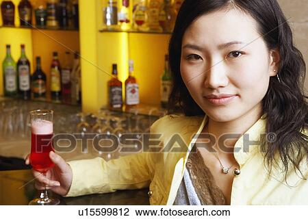 Stock Image - Portrait of a young woman holding a glass. Fotosearch