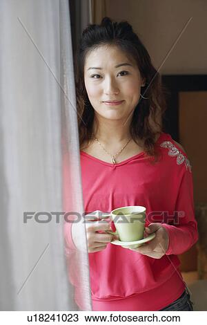 Stock Image - Portrait of a young woman holding a tea cup. Fotosearch