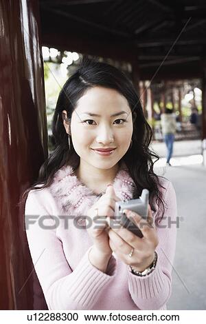 Portrait of a young woman operating a mobile phone with a digitized pen View Large Photo Image Stock Image - Portrait of a young woman operating a mobile phone with a digitized pen. Fotosearch