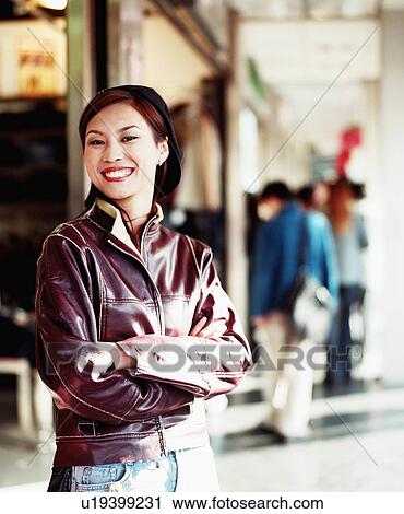 Portrait of a young woman smiling with her arms folded View Large Photo Image Stock Image - Portrait of a young woman smiling with her arms folded. Fotosearch