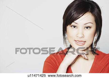 Stock Photography - Portrait of a young woman smiling with her hand under her chin. Fotosearch
