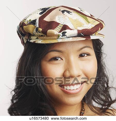 Stock Image - Portrait of a young woman wearing a cap and smiling. Fotosearch