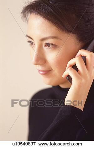 Stock Photo - Closed Up Image of a Mid Adult Woman Dressed in Black, Talking on the Phone, Side View, Smiling. Fotosearch