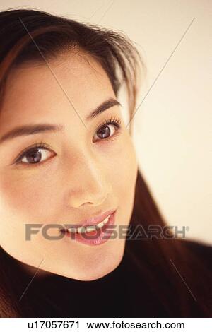 Stock Image - Closed Up Image of a Young Adult Woman Looking Sideways, Smiling, High Angle View. Fotosearch