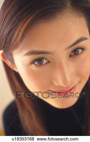 Stock Photo - Closed Up Image of a Young Adult Woman Smiling, Looking at Camera, High Angle View. Fotosearch
