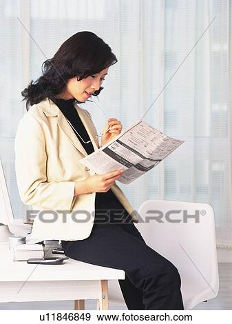 Image of a Business Woman Sitting on a Desk Reading a Worksheet, Side View View Large Photo Image Stock Photo - Image of a Business Woman Sitting on a Desk Reading a Worksheet, Side View. Fotosearch