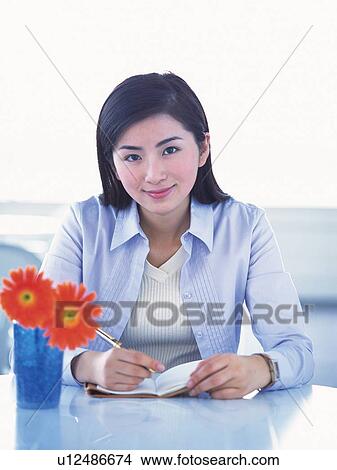 Picture - Image of a Business Woman Working at her Desk, Next to Some Orange-colored Flowers, Front View, Looking at Camera, Smiling. Fotosearch