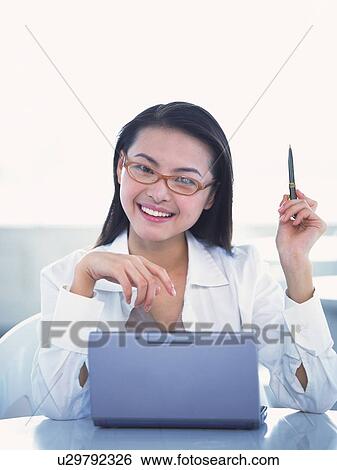 Stock Photograph - Image of a Businesswoman in a White Suite Wearing Red Glasses Holding a Pen, Looking at Camera, Smiling, Front View . Fotosearch