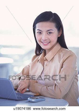 Image of a Businesswoman Working at her Computer, Looking at Camera, Smiling, Front View, Differential Focus View Large Photo Image Stock Photograph - Image of a Businesswoman Working at her Computer, Looking at Camera, Smiling, Front View, Differential Focus. Fotosearch
