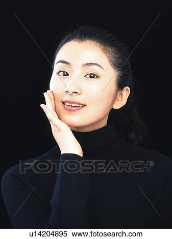 Stock Photography - Image of a Mid Adult Woman Dressed in Black, Holding her Face, Looking at Camera, Smiling, Front View. Fotosearch