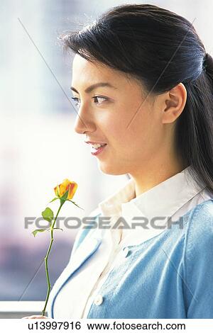 Image of a Mid Adult Woman Holding an Orange Rose, Looking Sideways, Smiling, Side View View Large Photo Image Stock Photograph - Image of a Mid Adult Woman Holding an Orange Rose, Looking Sideways, Smiling, Side View. Fotosearch