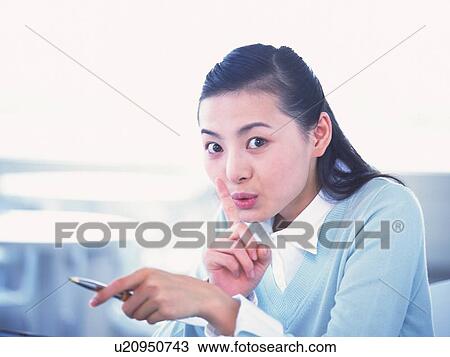 Stock Image - Image of a Young adult Woman About to Put her Finger on her Lip, Looking at Camera, Side View. Fotosearch