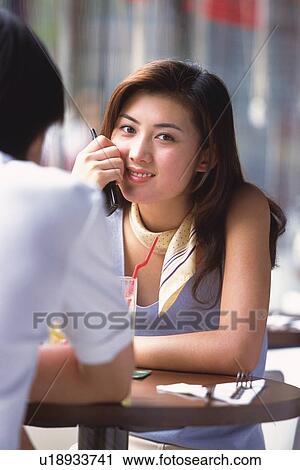 Stock Image - Image of a Young Adult Woman Having a Drink With a Man, Looking at Camera, Smiling, Front View, Rear View, Differential Focus. Fotosearch