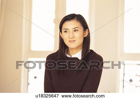 Stock Photo - Image of a Young Adult Woman In Front of a Window Looking Sideways, Smiling, Front View. Fotosearch