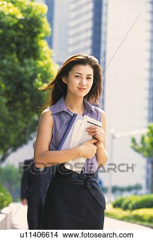 Image of a Young Adult Woman Outdoors, Holding a Newspaper, Looking at Camera, Smiling, Low Angle View, Differential Focus View Large Photo Image Picture - Image of a Young Adult Woman Outdoors, Holding a Newspaper, Looking at Camera, Smiling, Low Angle View, Differential Focus. Fotosearch