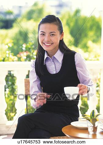 Stock Image - Image of a Young Adult Woman Outdoors, Drinking a Cup of Coffee, Smiling, Front View, Looking at Camera, Differential Focus. Fotosearch