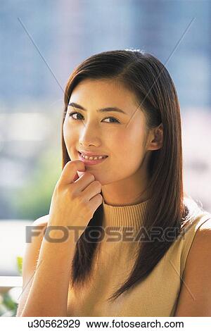 Stock Photo - Image of a Young adult Woman Outdoors, Posing, Looking at Camera, Smiling, Side View. Fotosearch