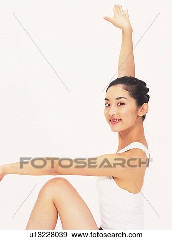 Stock Photo - Image of a Young Adult Woman Posing In Front of a White Wall, Side View, Smiling, Looking at Camera. Fotosearch