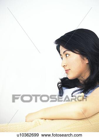 Image of a Young Adult Woman Sitting In Front of a White Wall, Looking Sideways, Side View, Smiling, Copy Space View Large Photo Image Stock Photo - Image of a Young Adult Woman Sitting In Front of a White Wall, Looking Sideways, Side View, Smiling, Copy Space. Fotosearch